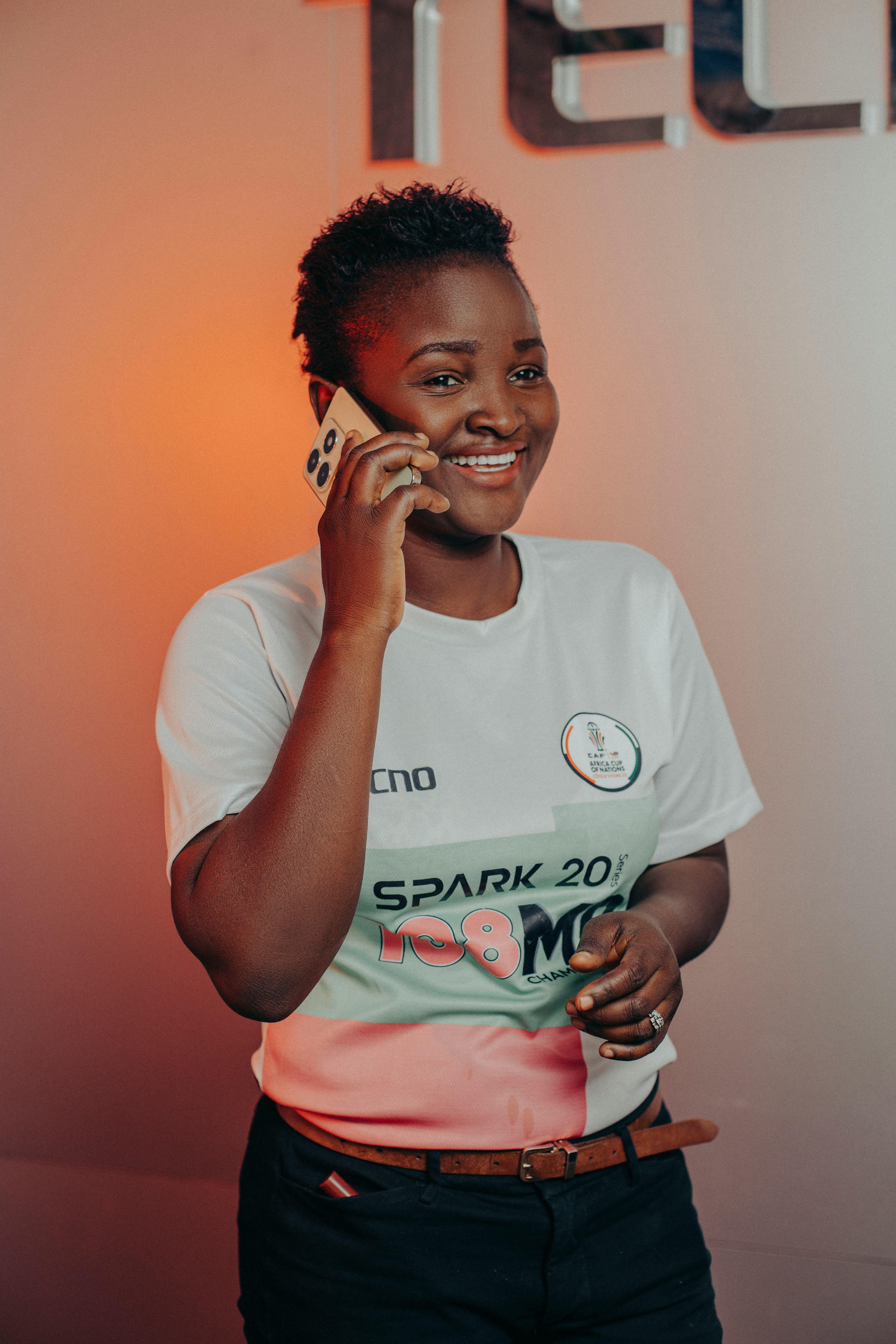 Free Happy woman talking on a smartphone in a casual setting. Indoor environment with warm lighting. Stock Photo