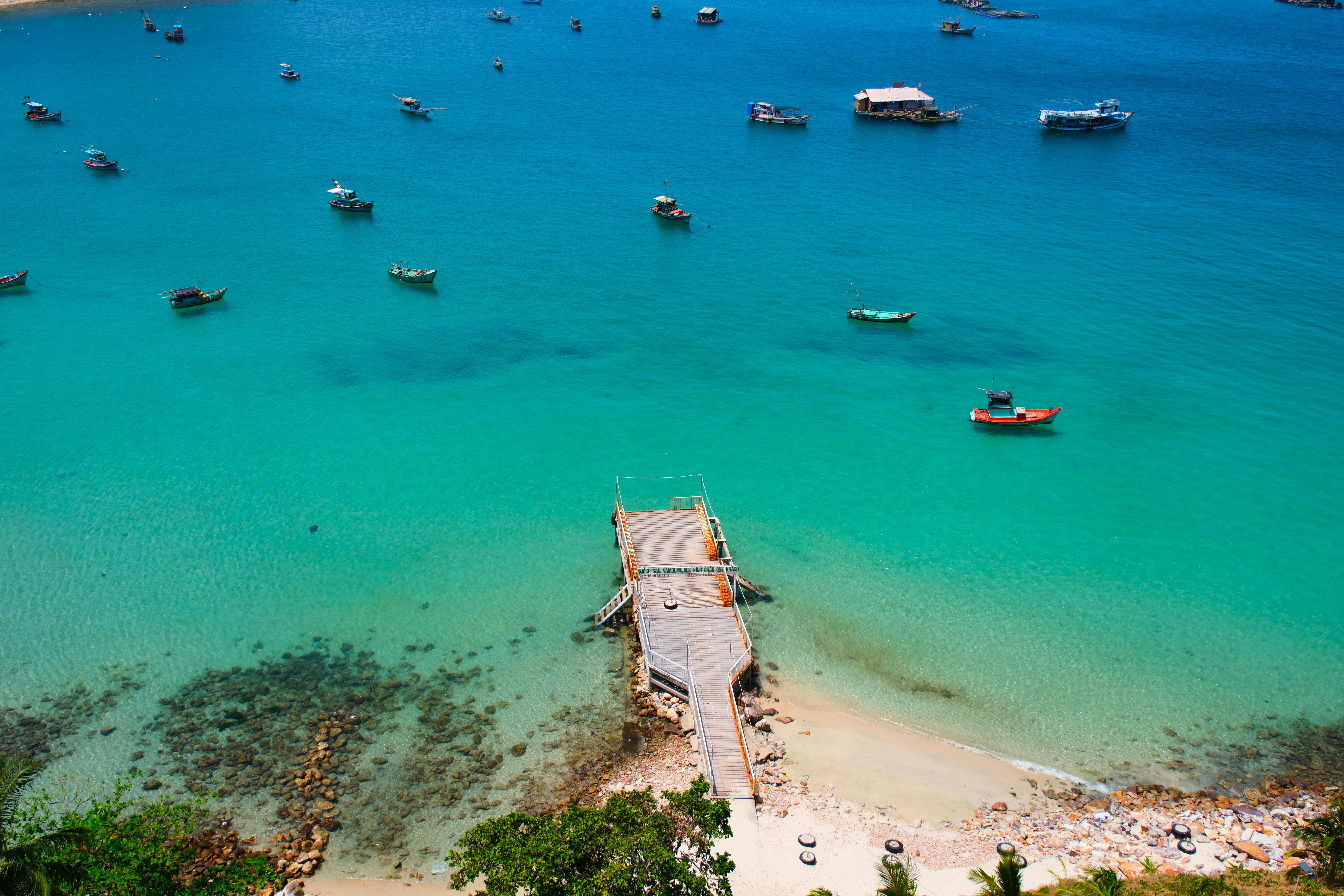 Stunning aerial view of a dock surrounded by boats and crystal-clear blue ocean water.