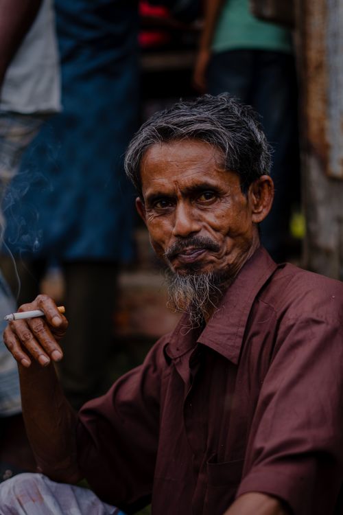 Free Rustic portrait of a contemplative senior man smoking a cigarette outdoors, conveying a introspective mood. Stock Photo