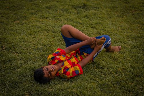 Free A boy in colorful attire enjoys a playful moment lying on grass, outdoors. Stock Photo