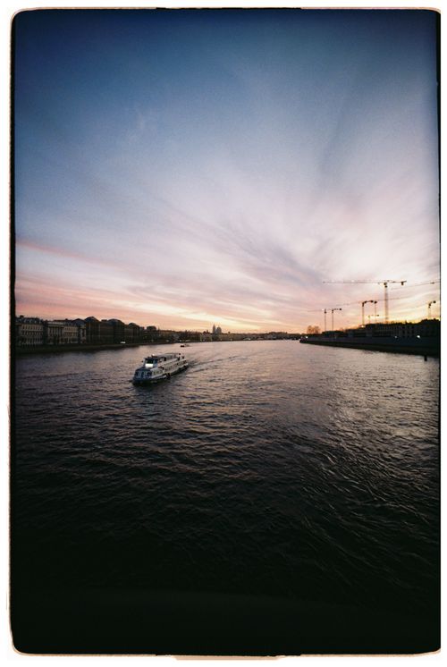 Free Boat sailing on a serene river during twilight with a colorful sky. Stock Photo