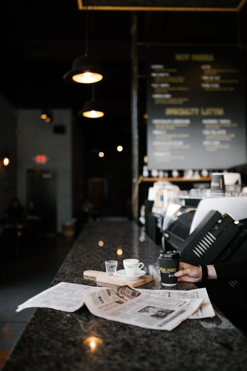 Free Relaxing coffee shop ambiance in Greensboro, featuring espresso and a newspaper on a marble counter. Stock Photo