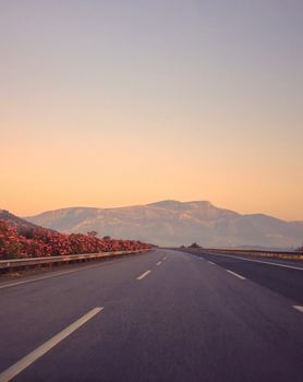 A peaceful highway in Aydın, Türkiye, with mountain and floral views at sunrise, evoking calmness.