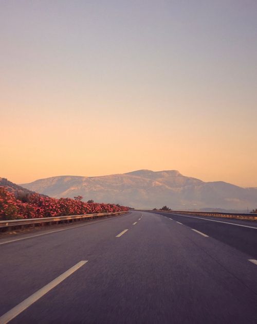 Free A peaceful highway in Aydın, Türkiye, with mountain and floral views at sunrise, evoking calmness. Stock Photo