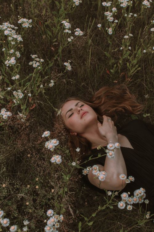 Free Serene woman lying amidst white wildflowers, evoking peace and nature. Stock Photo
