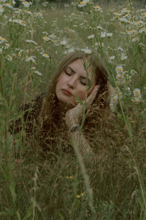 Free A tranquil scene of a woman resting with closed eyes in a lush wildflower meadow. Stock Photo