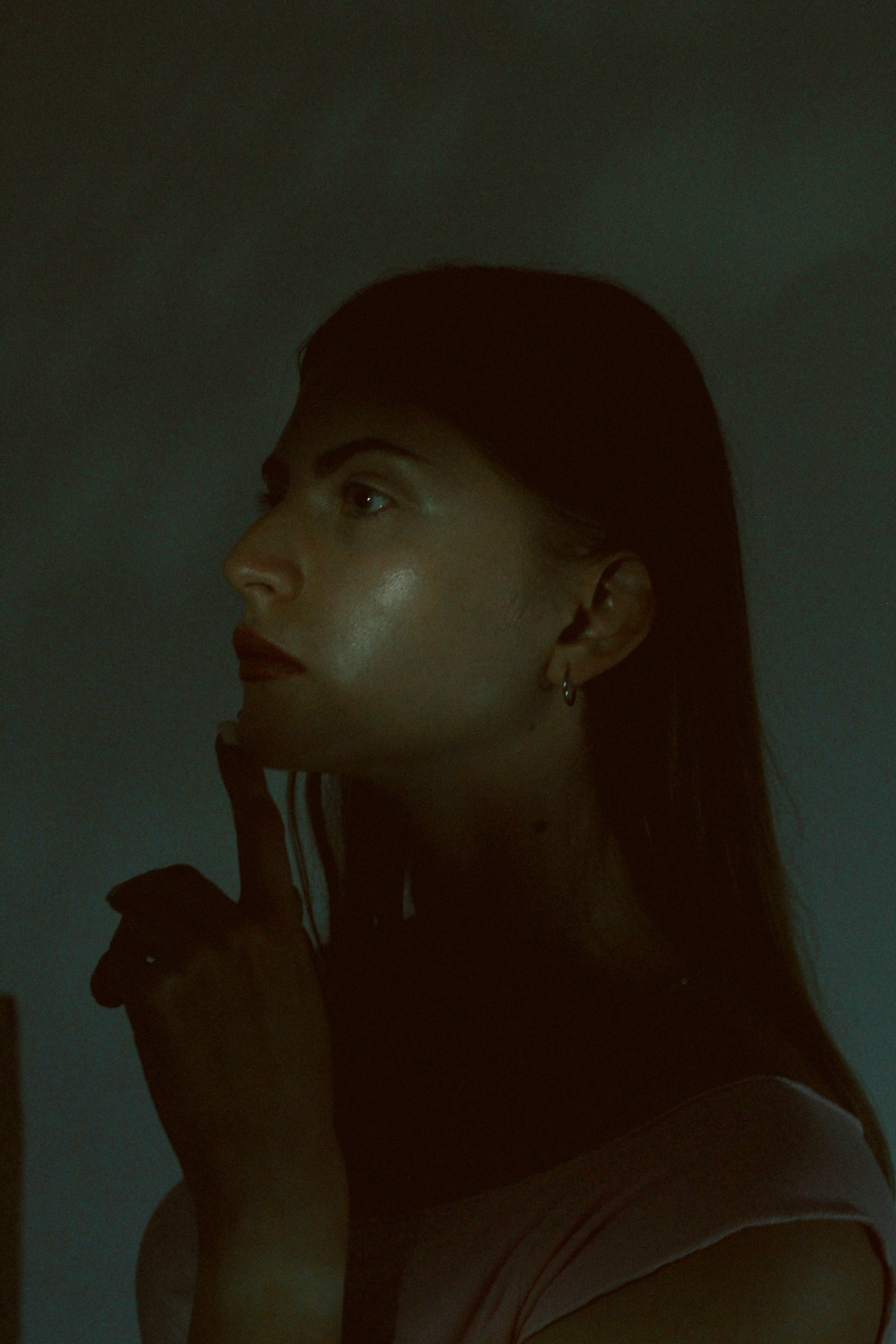 A thoughtful woman in profile poses in a dark, moody atmosphere. - 5 Human-Only Skills That AI Can Never Replace (My Expert Take).