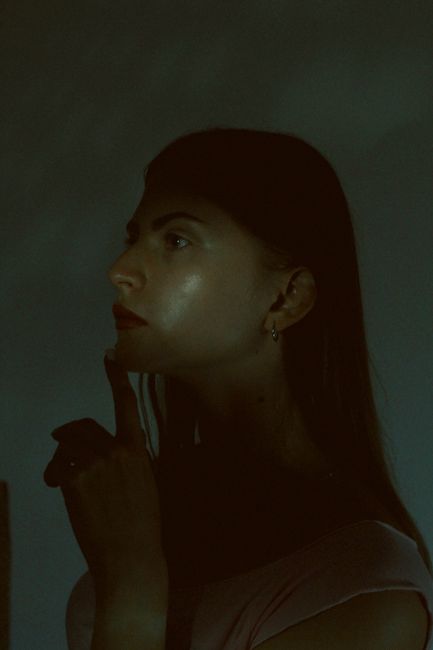 A thoughtful woman in profile poses in a dark, moody atmosphere. - 5 Human-Only Skills That AI Can Never Replace (My Expert Take).