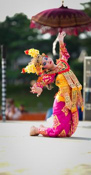 A vibrant Balinese dancer performing under an umbrella in Jakarta, Indonesia.
