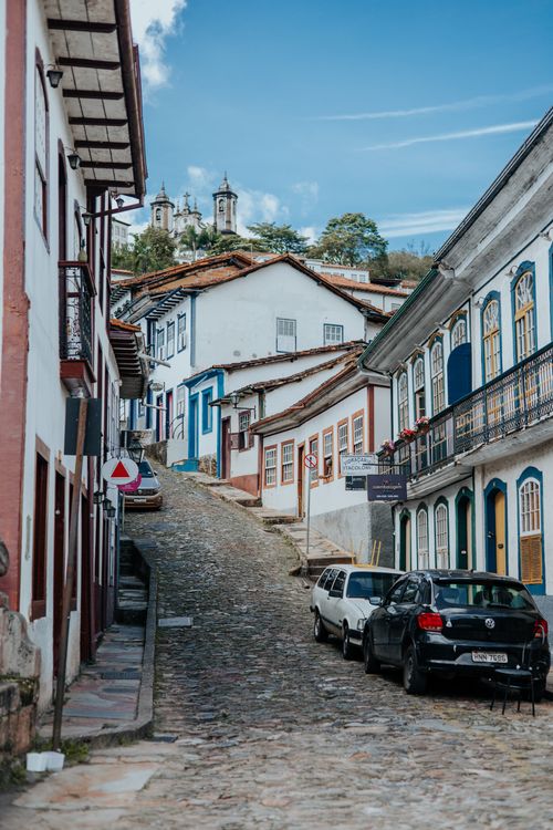 Free Picturesque cobblestone street in Ouro Preto with colorful colonial architecture and church towers in view. Stock Photo