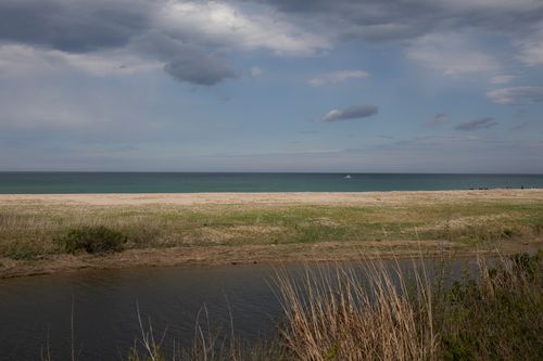Free Serene seaside scene with sandy beach, ocean waves, and dramatic cloudy sky. Stock Photo