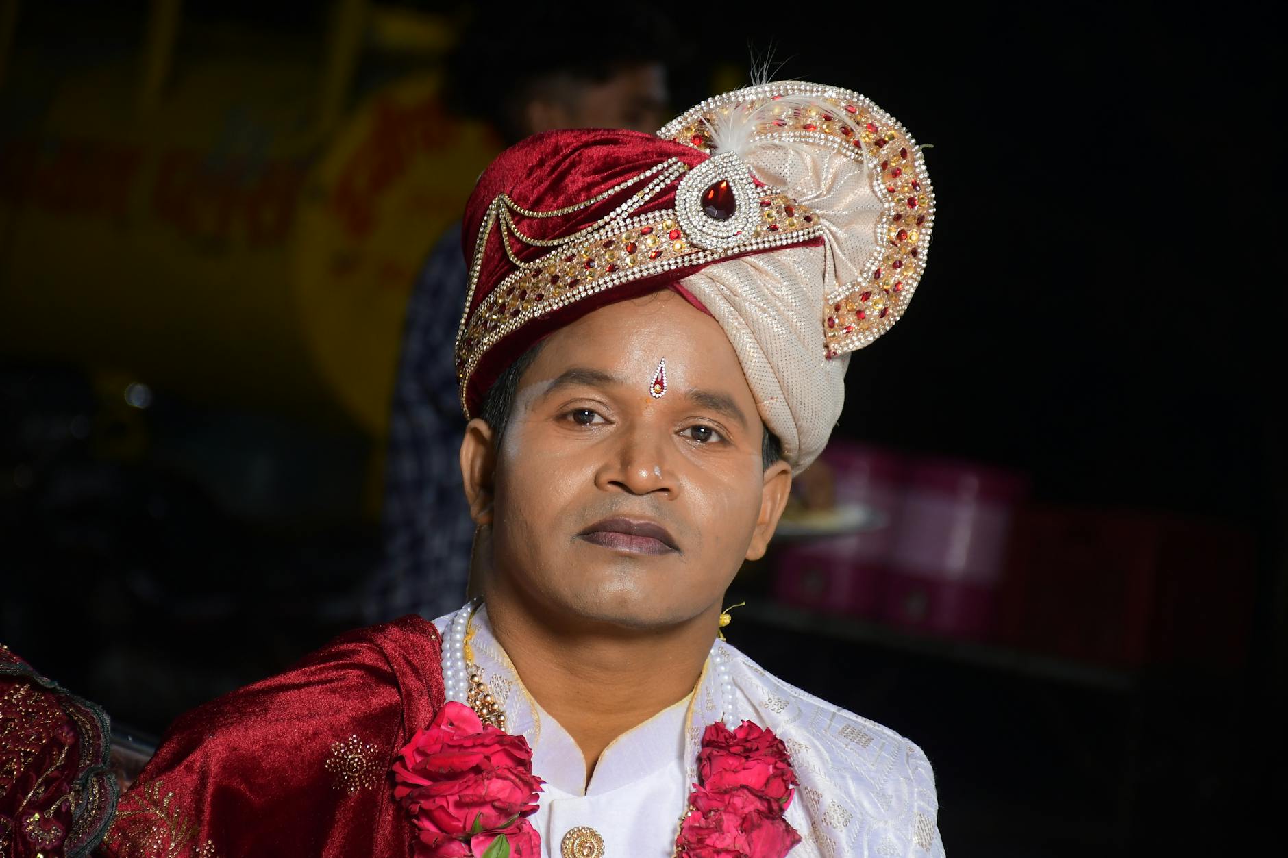 Portrait of a groom in traditional South Asian wedding attire with ornate turban and jewelry.