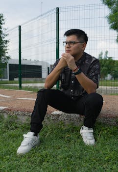 Man wearing glasses and black shirt sitting thoughtfully in a park in Merida, Yucatan.