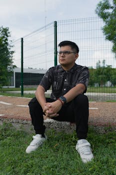 Portrait of a man sitting pensively in a park in Merida, Yucatan, wearing glasses and a watch.
