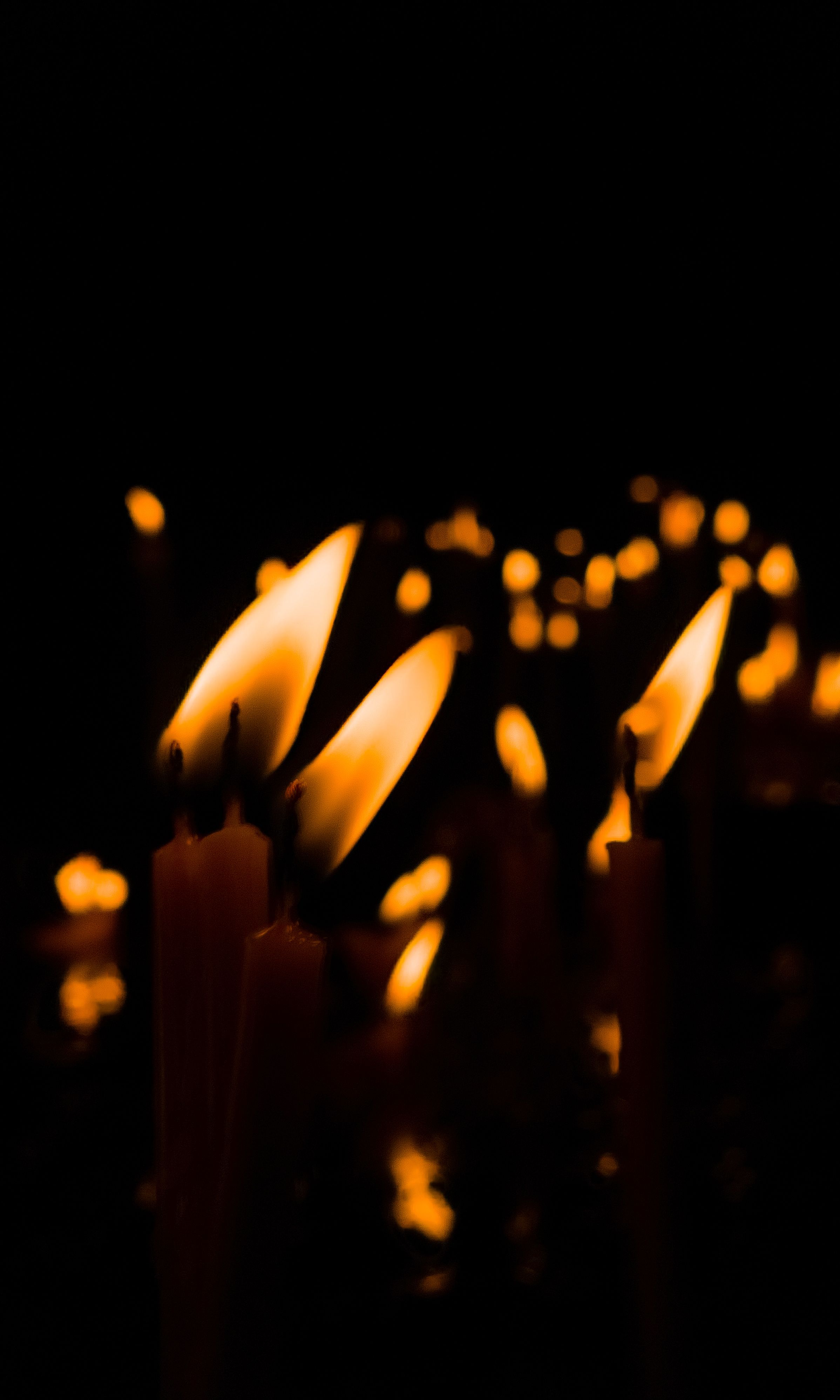 Warm candle flames creating a peaceful, reflective atmosphere in darkness.