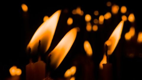 Warm candle flames creating a peaceful, reflective atmosphere in darkness.
