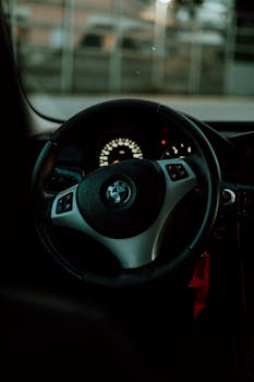 Interior view of a car steering wheel with dashboard lights glowing.