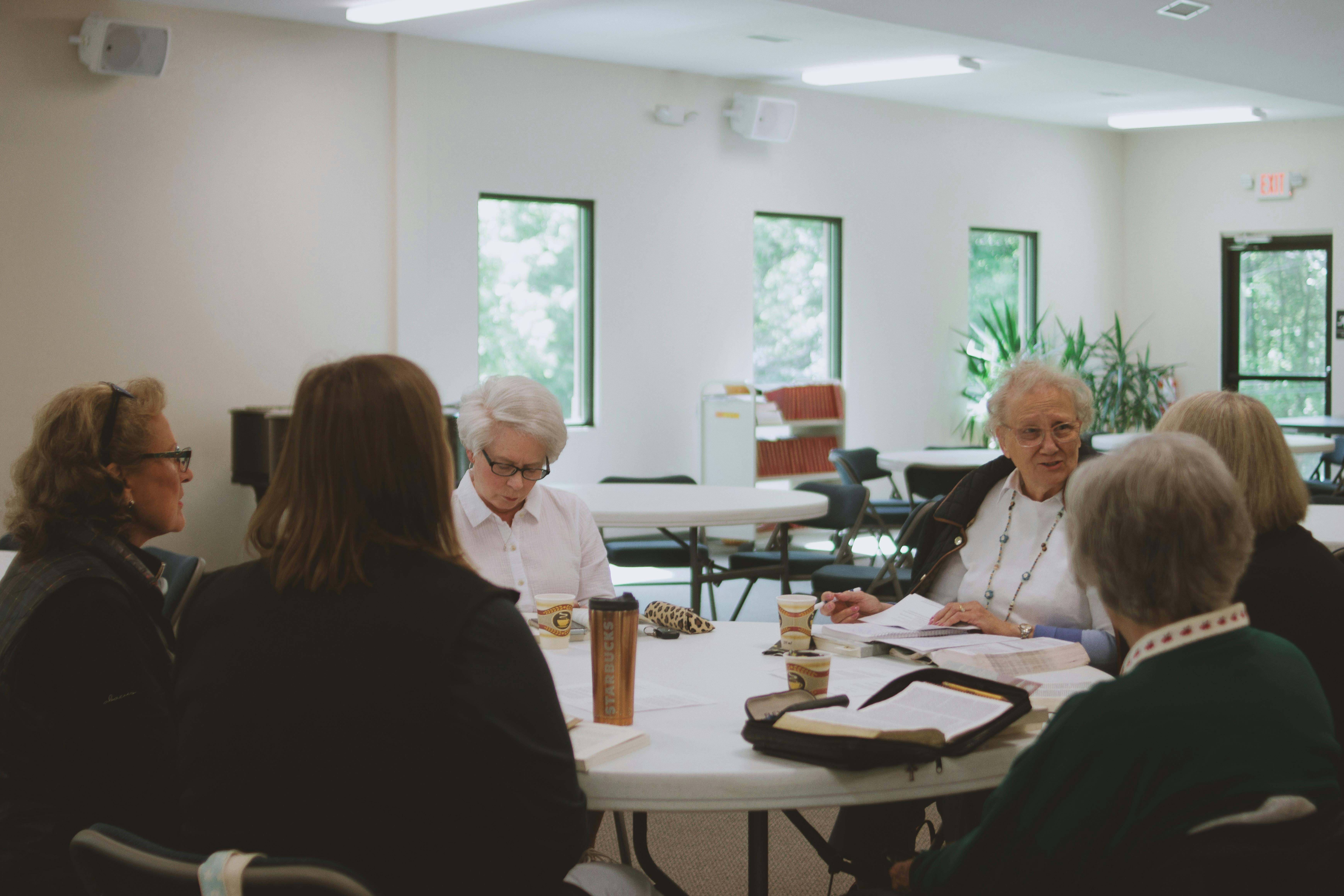Group of women participating in a Bible study session indoors, fostering community and spiritual growth.
