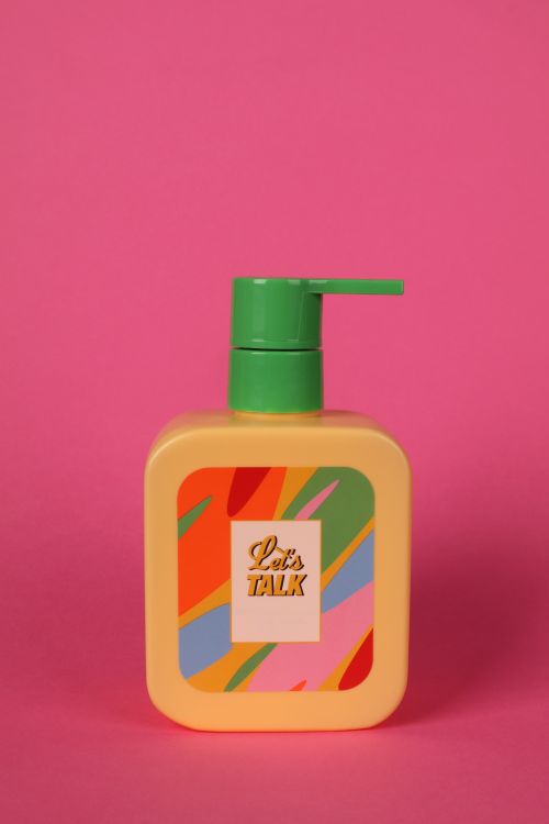 Free Vibrant soap dispenser with multicolored label against a pink background, promoting a lively vibe. Stock Photo