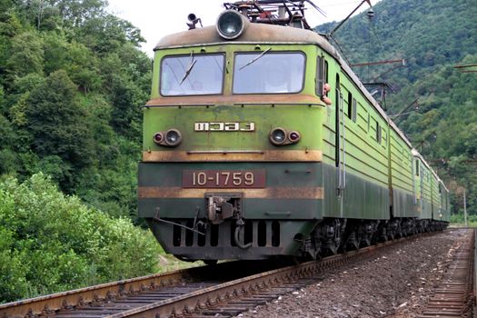 A classic Soviet-era locomotive traveling through lush forests in Kharagauli, Georgia.