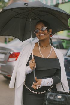 Chic urban fashion with a woman holding an umbrella in a city setting, exuding elegance and charm.