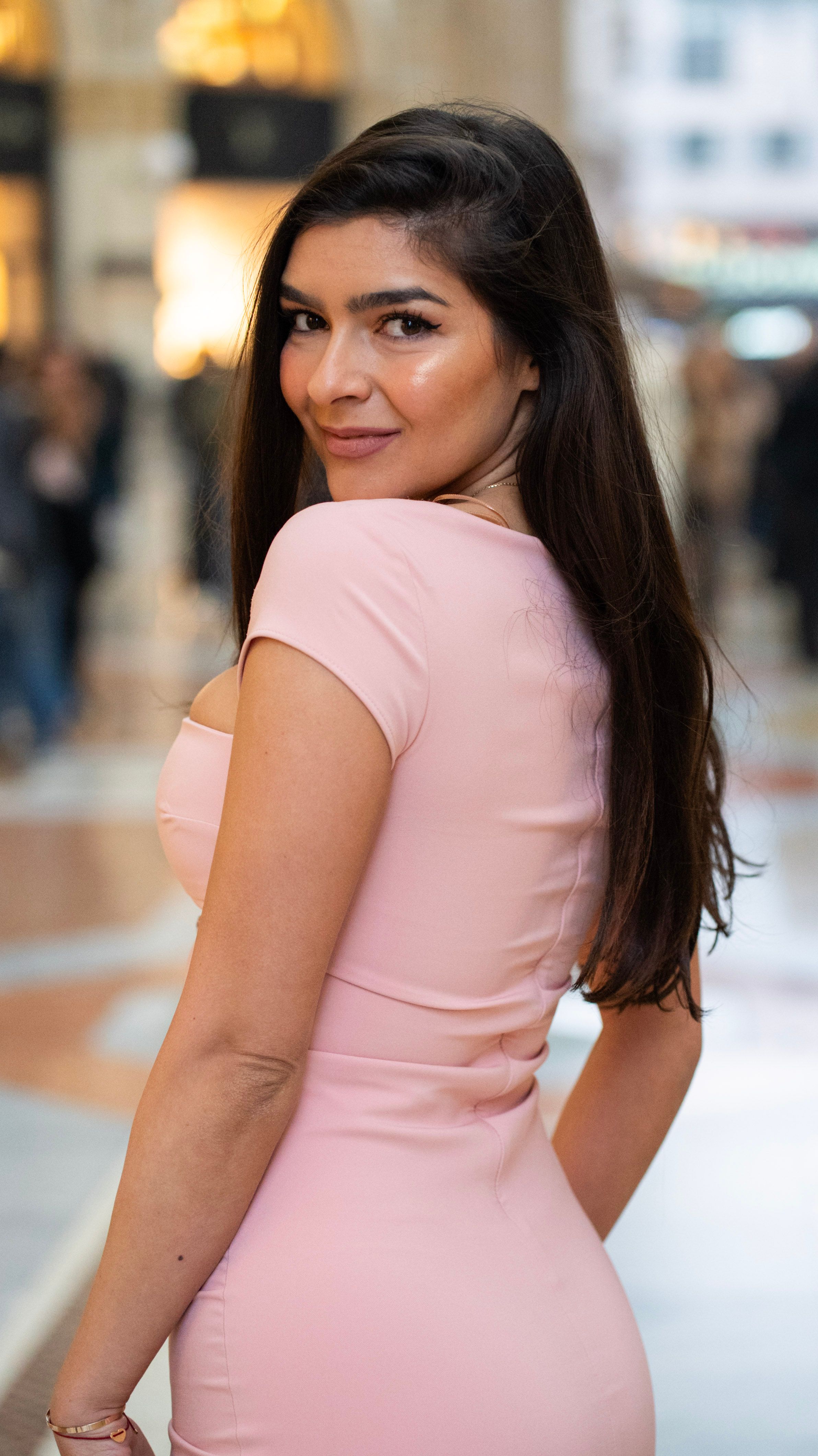Stylish young woman in pink dress at famous Galleria in Milan, showcasing fashion and elegance.