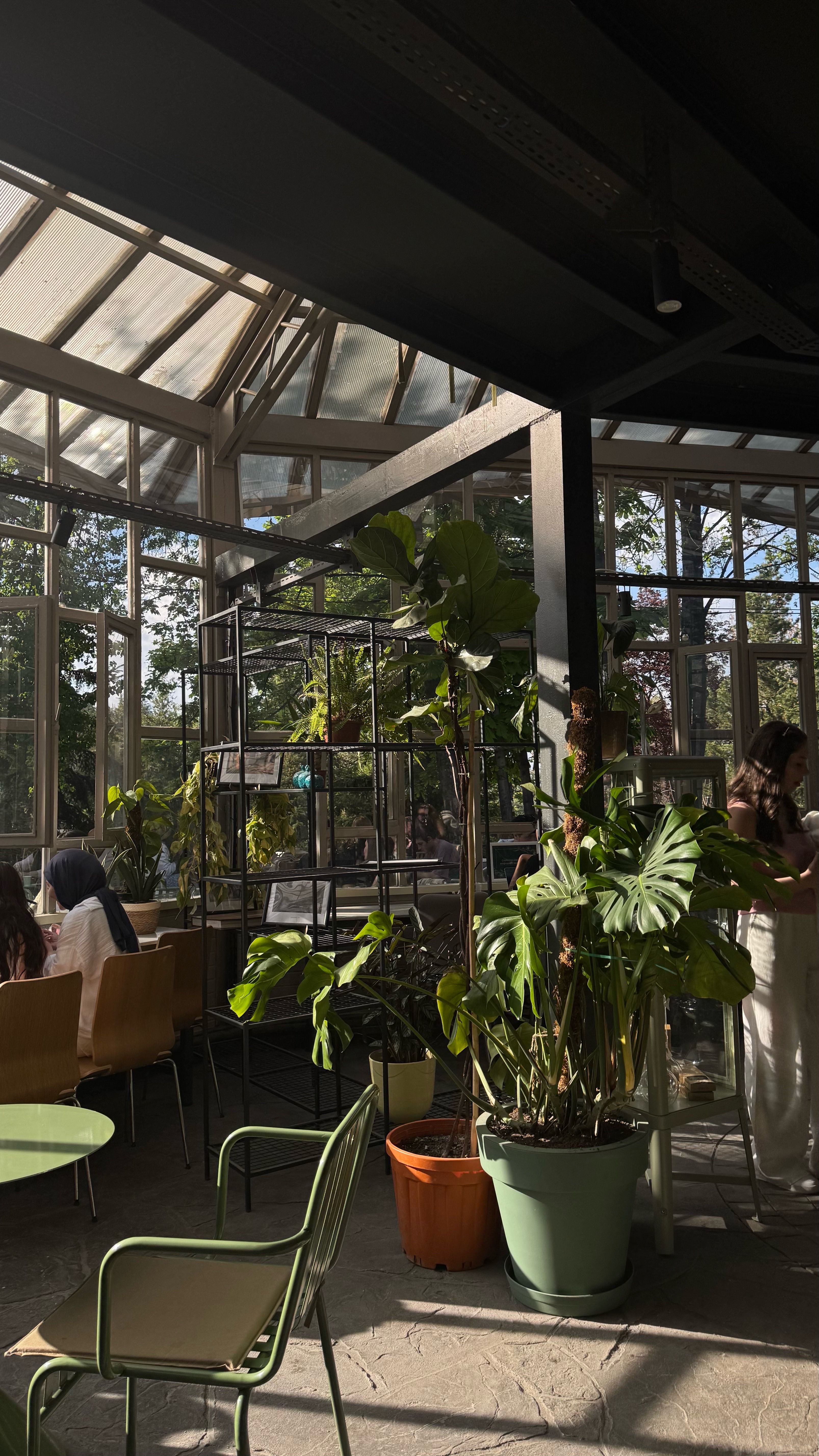 Bright greenhouse cafe featuring lush indoor plants and sunlit spaces.