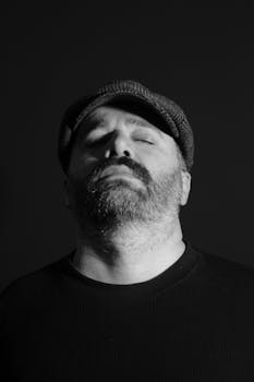 A black and white portrait of a man wearing a hat with a serene expression, captured in Ankara, Türkiye.