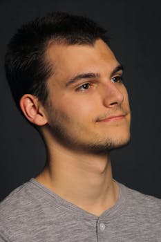 Portrait of a young man with a reflective expression against a dark background.