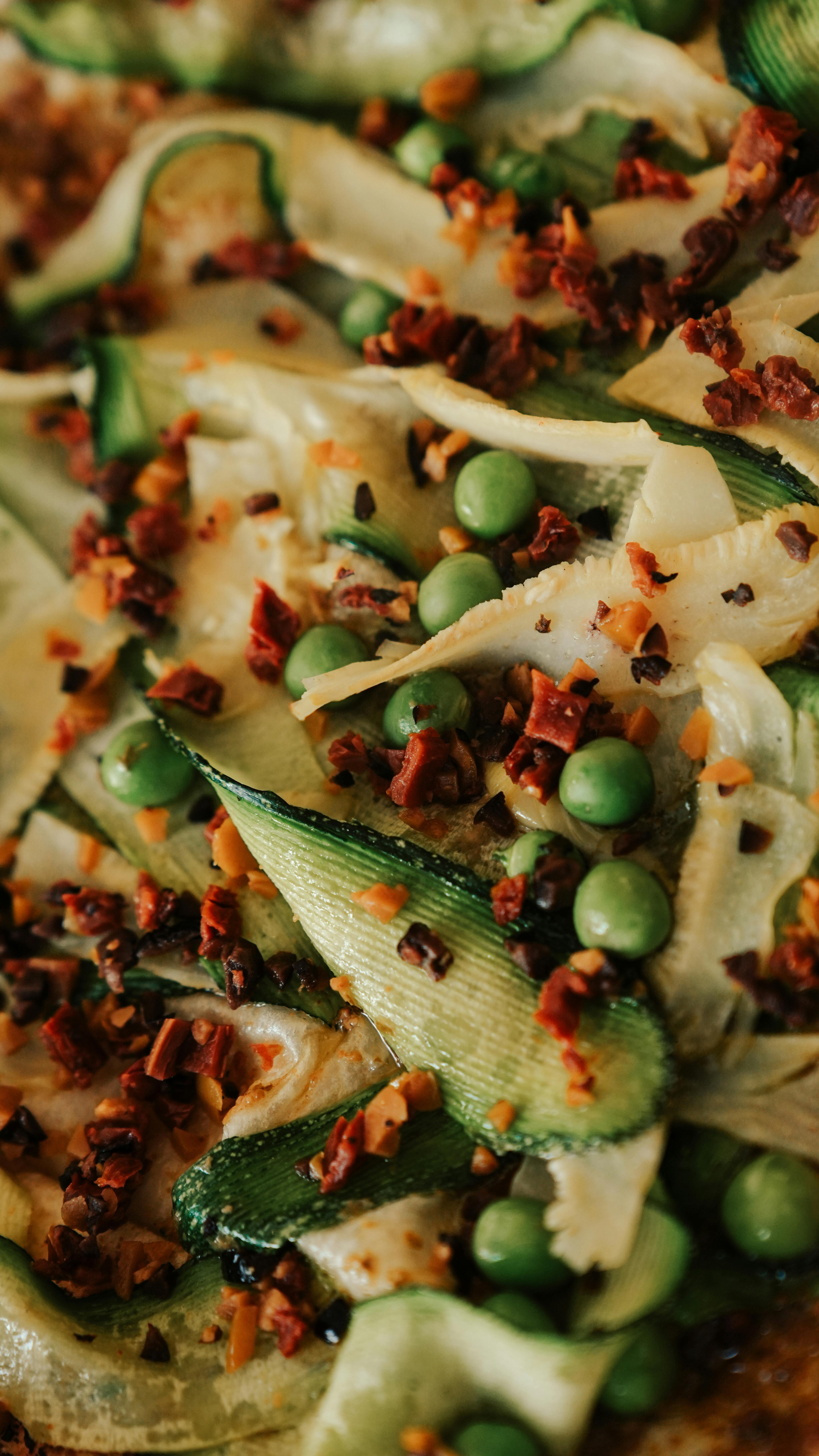 Close-up of gourmet veggie pizza topped with zucchini, peas, and spices. Perfect for food lovers.