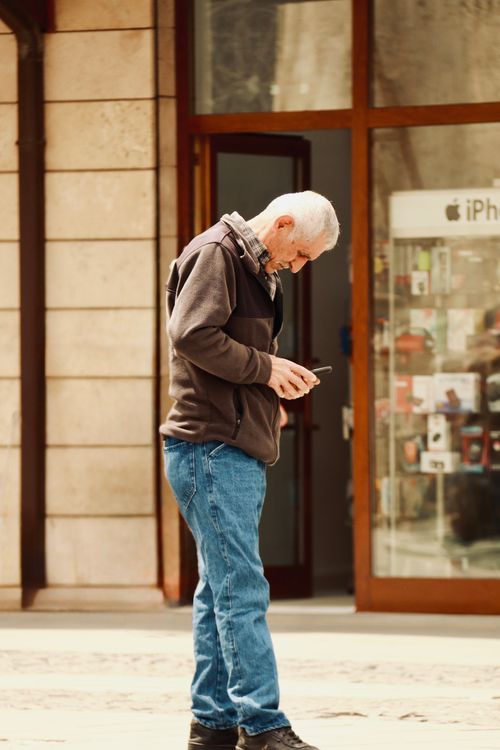 Free A senior adult using a smartphone outside an iPhone shop in Konya, Türkiye. Stock Photo