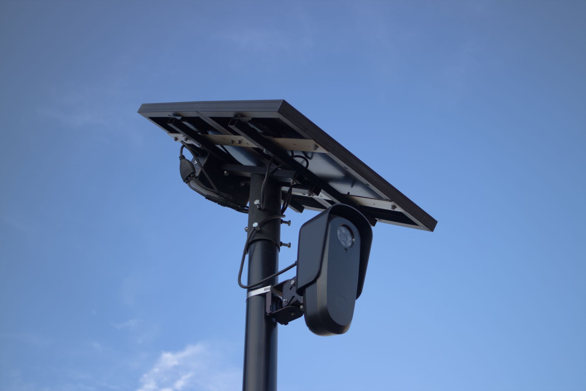 Solar-powered surveillance camera with a clear blue sky backdrop, highlighting modern technology.