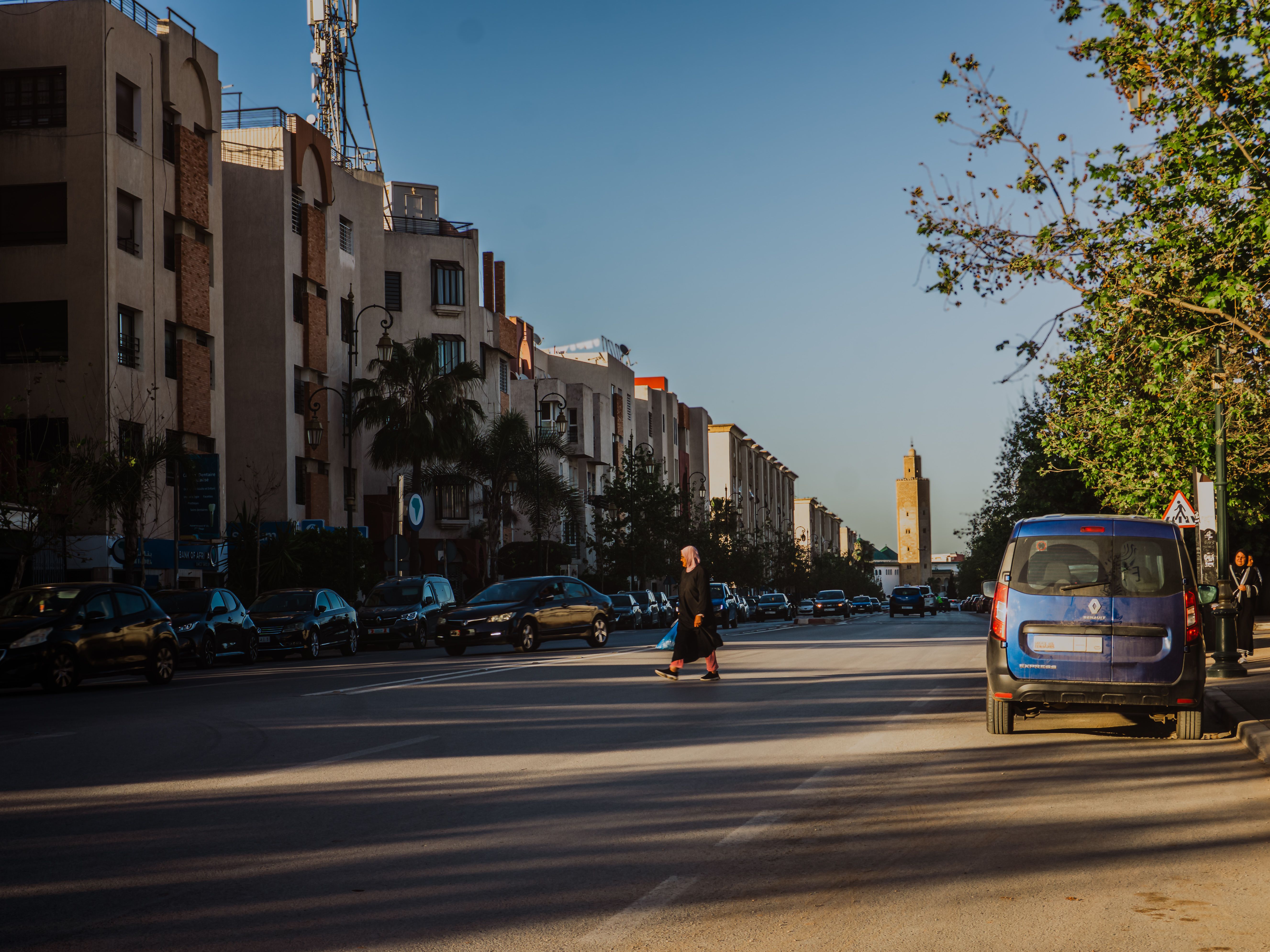 A vibrant street in Rabat, Morocco with a visible minaret in the background under a clear day.