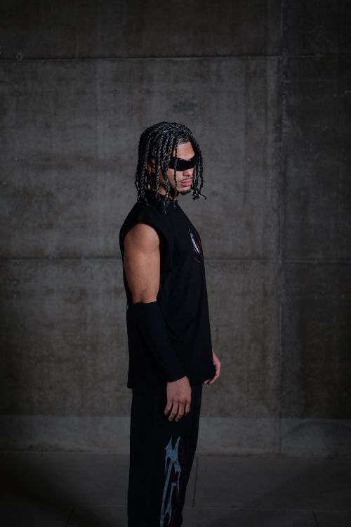 Free Cool young man with braids and sunglasses poses in urban setting. Stylish fashion. Stock Photo