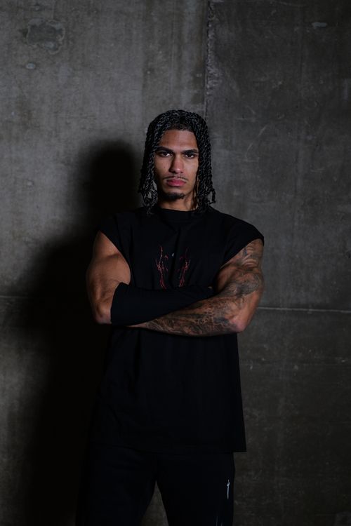 Free Portrait of a confident young man standing against a grunge concrete wall, arms crossed. Stock Photo