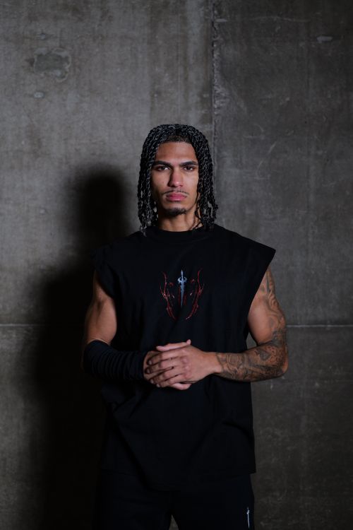 Free A man with braided hairstyle posing confidently against a concrete wall. Stock Photo