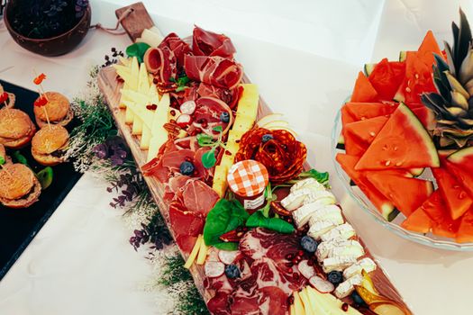 Appetizing charcuterie board featuring meats, cheeses, and fresh fruit slices for a gourmet snack.