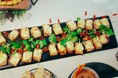 Free Gourmet appetizers on black platter garnished with pecans and greens. Stock Photo