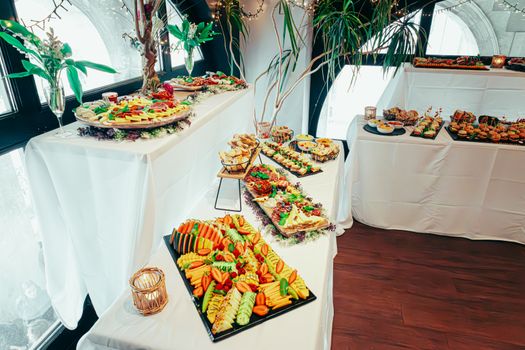 Elegant indoor buffet with diverse cuisines, vibrant decor, and fresh plant arrangements.