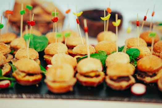 Delicious mini burgers with colorful skewers presented at a party or catering event.