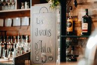 A cozy bar interior featuring a variety of alcohol bottles and a decorative sign reading 'Les Jardins d'Avalon'.