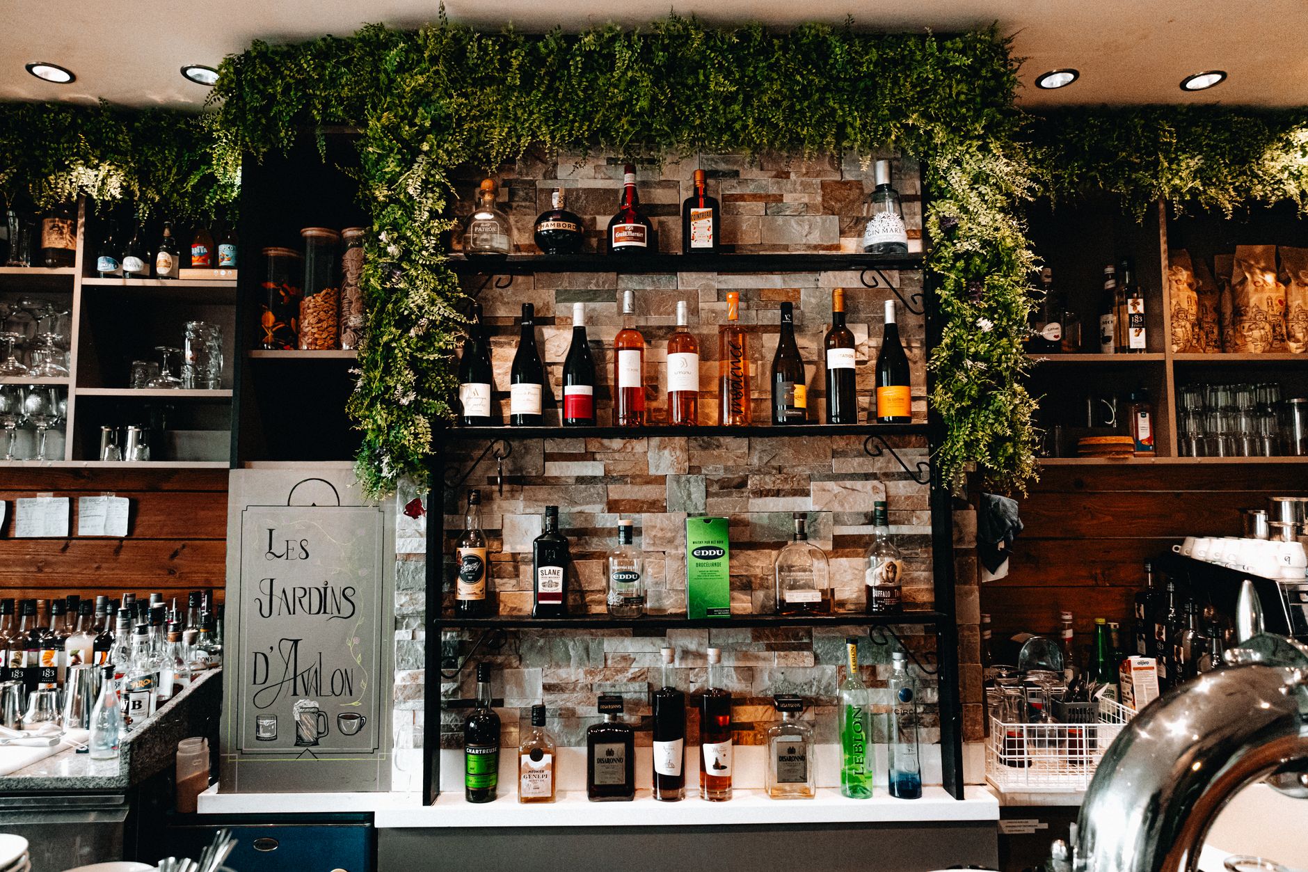 Elegant bar interior with various liquor bottles on shelves, decorated with greenery.