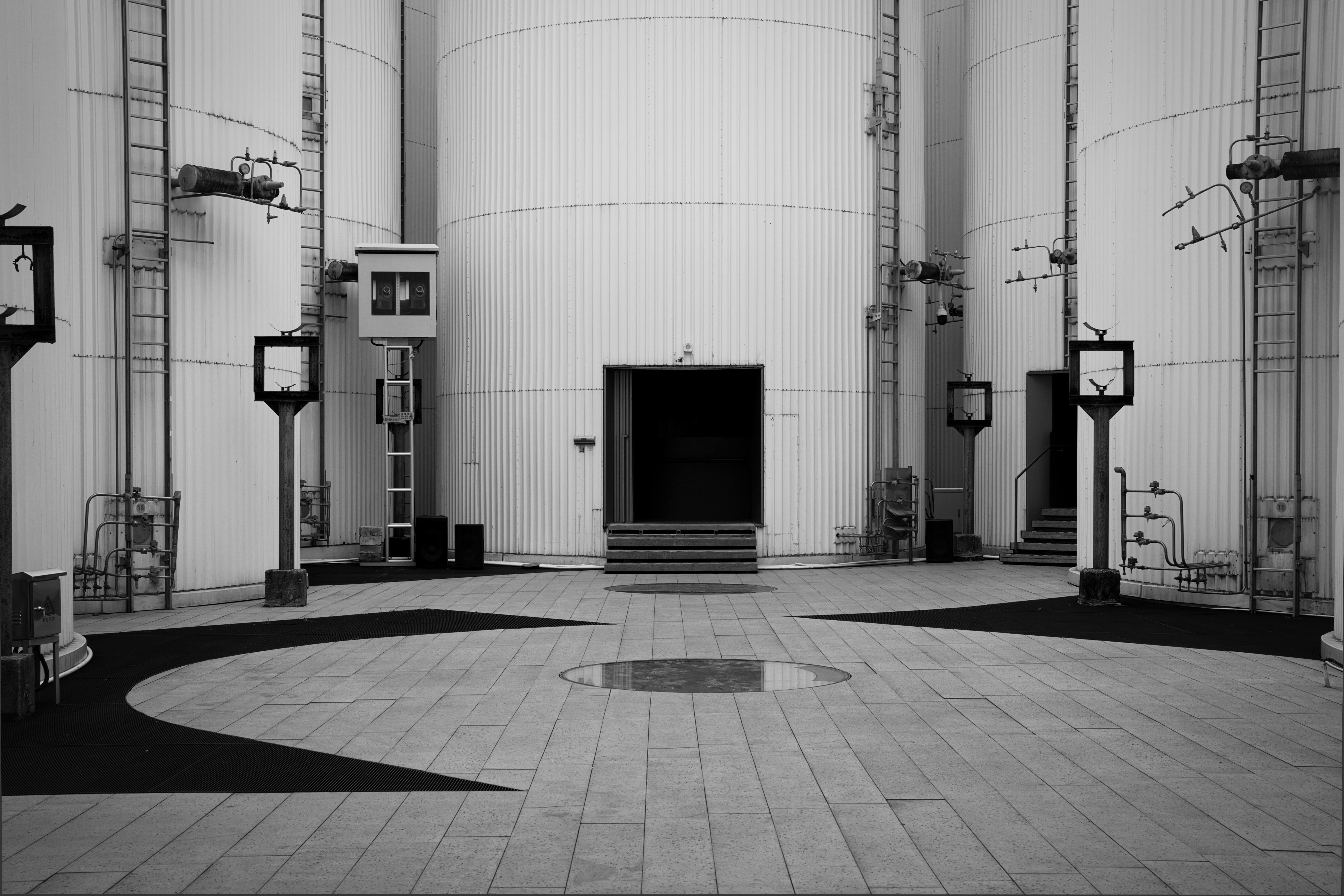 common:alt.prefix Schwarzweißbild von Industrietanks mit Rohren und Leitern. common:alt.postfix