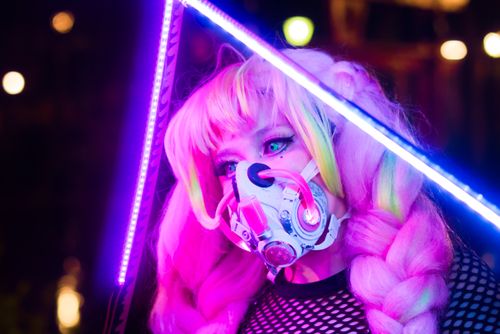 Free Cosplayer in neon lighting with cyberpunk mask at night, capturing a futuristic aesthetic. Stock Photo
