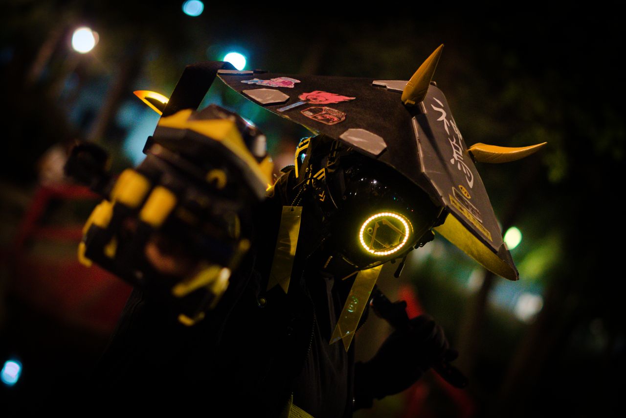 a person in neon cyberpunk costume poses dramatically at night