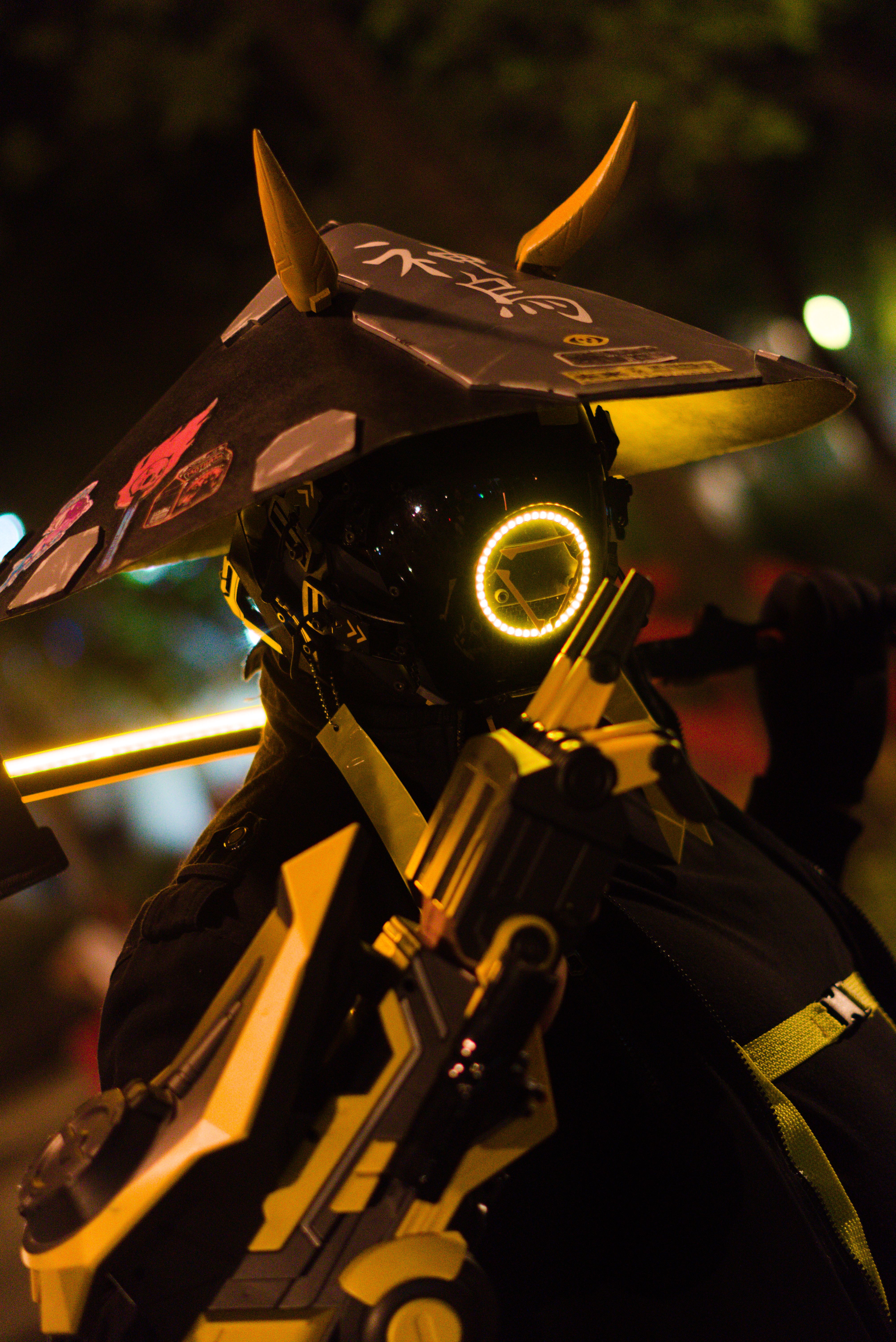 A person in a futuristic LED-illuminated samurai costume posing dramatically at night.