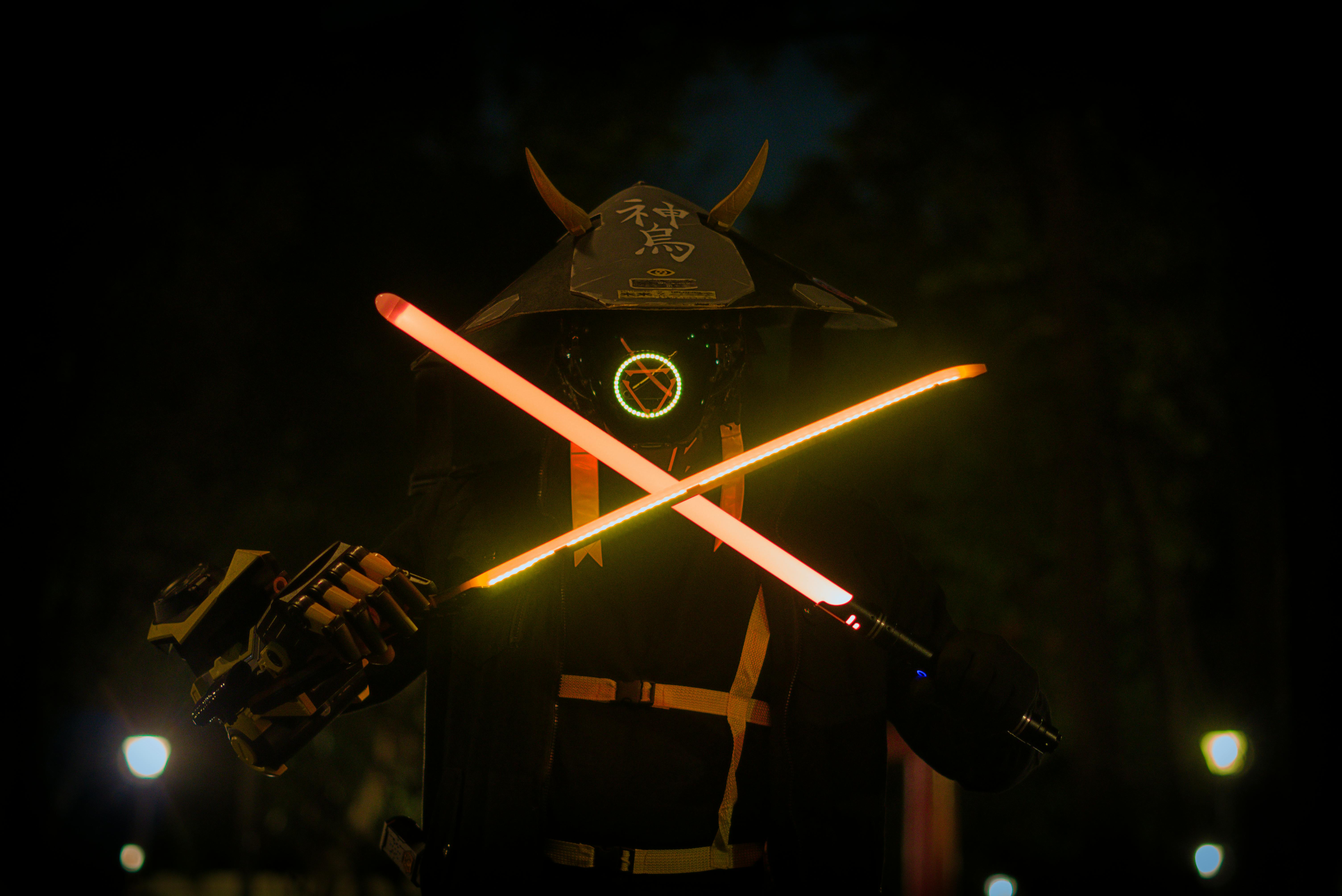 A futuristic samurai in a helmet and mask holding glowing neon swords at night.