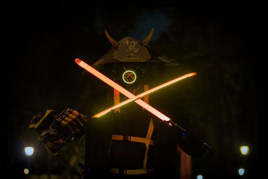 A futuristic samurai in a helmet and mask holding glowing neon swords at night.