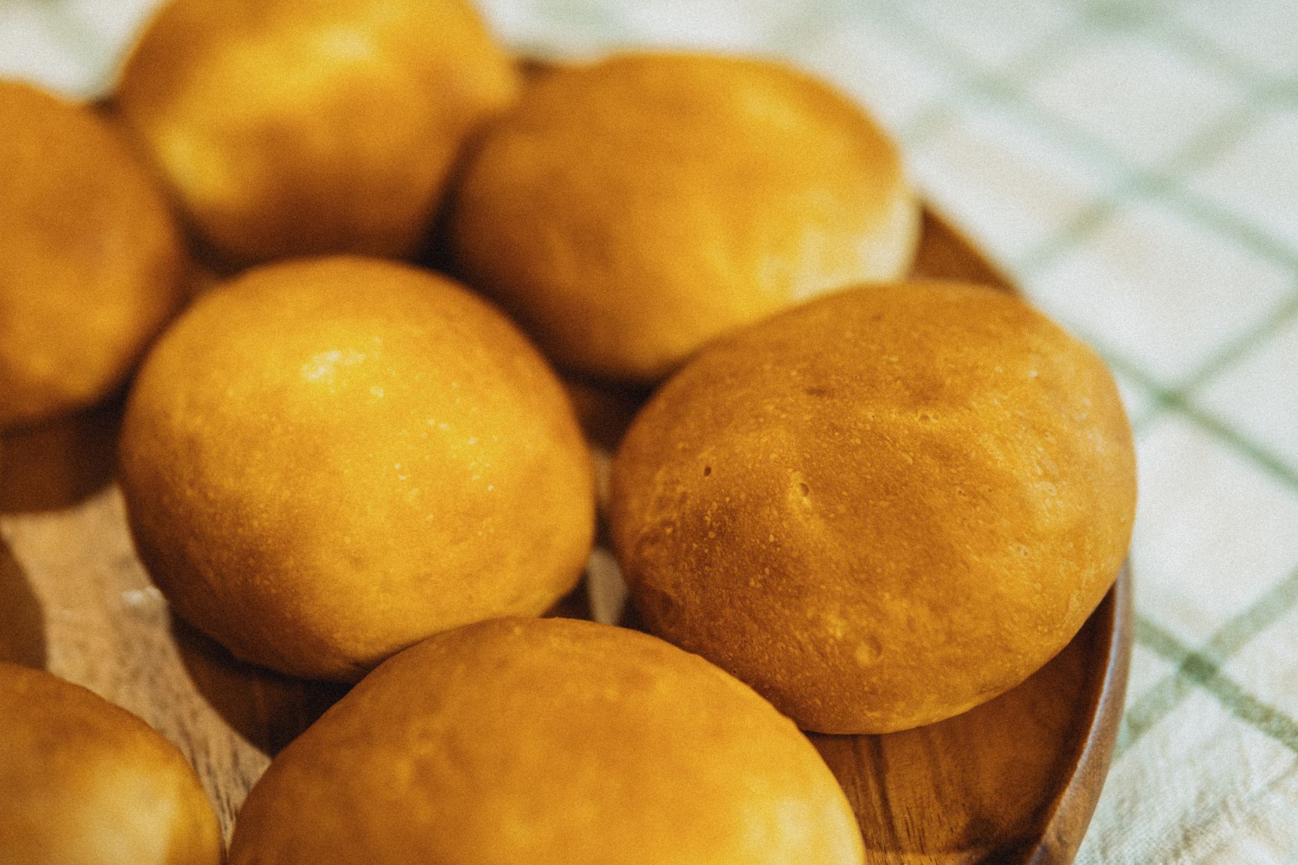 Delicious golden brown bread rolls freshly baked and displayed on a wooden plate, perfect for any kitchen setting.