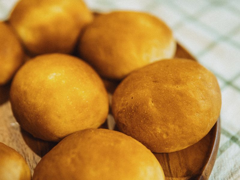 Golden brown bread rolls freshly baked on a wooden plate